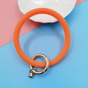 Detail of orange silicone wristband keychain with gold spring buckle and mini pendant