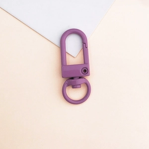 Gros plan d'un fermoir mousqueton en métal violet foncé avec une base rotative à 360°