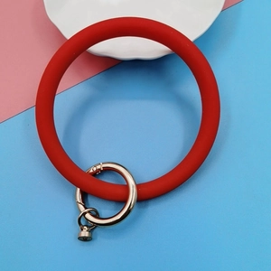 Detail of red silicone wristband keychain with silver metal clasp on pastel background