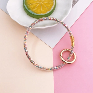 Macro detail of clear resin keychain filled with colorful glitter and gold spring buckle