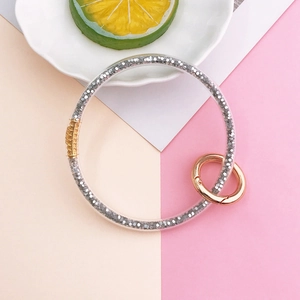 Macro detail of a clear silicone keychain bracelet with silver glitter and gold metal hardware