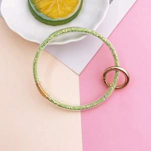 Detail of green glitter filled transparent soft glue bracelet keychain with gold spring clasp