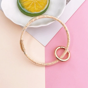 Detailed macro view of clear resin keychain ring filled with sparkling gold sequins