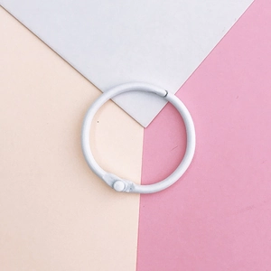 Close-up of a white painted metal binder ring for DIY crafts on a pastel geometric background