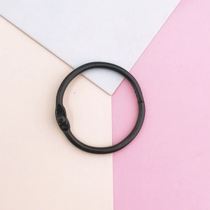 Detail of a black metal hinged binder ring for DIY crafts on a pastel geometric background
