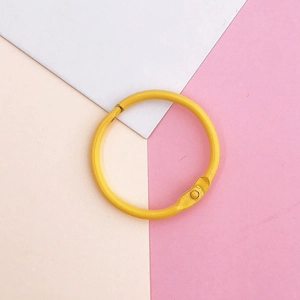 Detail view of a yellow lacquered metal binder ring with a hinged opening for DIY crafts