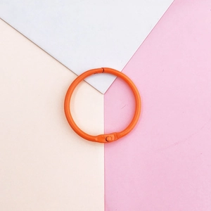 Top view of orange painted metal round binder ring on geometric pastel background