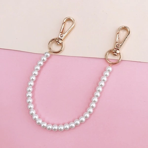 Detailed view of white pearl phone case chain with gold lobster clasps and rings