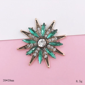 Detailed macro view of vintage sunburst brooch with emerald green crystals, 39x39mm size