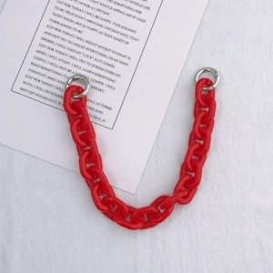 Detail of red acrylic thick chain with silver metal buckles on white fabric background