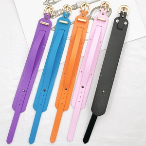 Détail de bracelets en cuir colorés en violet, bleu, orange, rose et noir avec boucles dorées