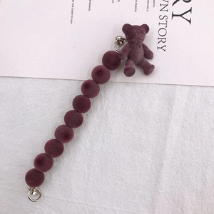 Dettaglio del cinturino per cellulare con perle di peluche e ciondolo a forma di orso