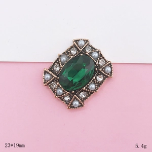 Macro detail of vintage emerald jewel accessory with white rhinestones and pearls