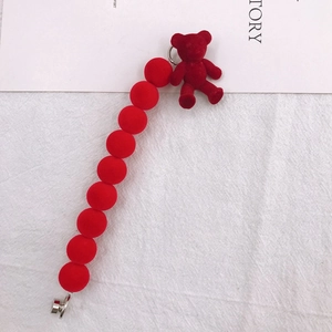 Dettaglio di un ciondolo a forma di orso rosso floccato e perle per catene per cellulari