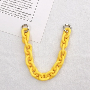 Macro detail of a bright yellow acrylic chain strap with silver circular spring clasps