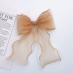 Detailed view of champagne organza bow with wavy edges and long elegant ribbons