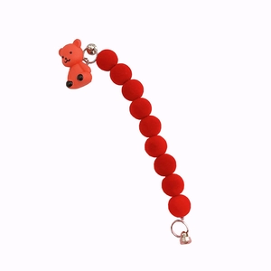 Red flocked bead phone chain with cute bear charm and silver bell on white background