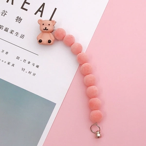 Close-up of pink flocked beaded phone strap with cute 3D bear charm and silver metal ring
