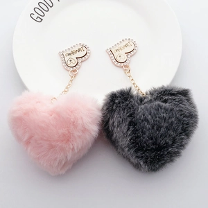 Macro shot of plush heart charms in pink and grey with I love you rhinestone pendants