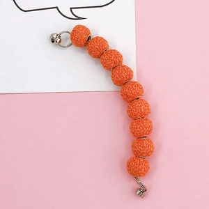 Detailed view of orange woven yarn ball charms with metal rings and spring clasps for phone cases