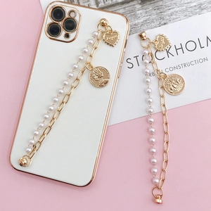 White phone case with gold camera ring, pearl beads, and vintage portrait coin chain charm