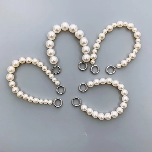 Detailed view of four white faux pearl chains with silver metal rings for phone cases