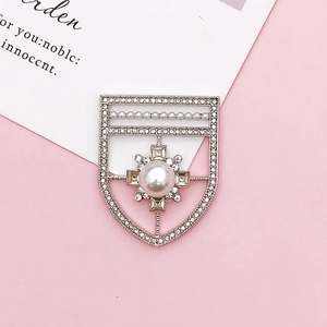 Dettaglio macro di una spilla a scudo d'argento con perle e strass scintillanti