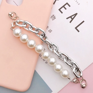 Dubbellaagse zilveren metalen ketting en witte parelarmband op een roze hoesje