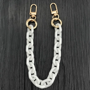 Detailed macro view of white acrylic large link chain strap with gold lobster clasps