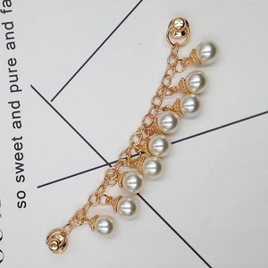 Close-up of golden fringe chain with seven round pearls and decorative floral caps