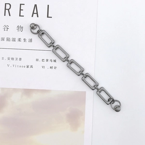 Dettaglio del bracciale a catena geometrica in lega di zinco grigio scuro su sfondo rivista