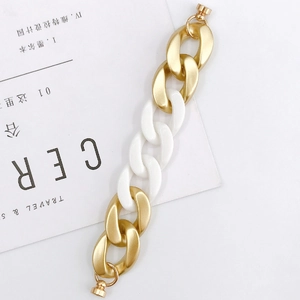 Detail of chunky gold and white acrylic chain with magnetic clasp on minimalist background