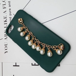 Detail view of dark green phone case with gold metal chain and white faux pearl charms