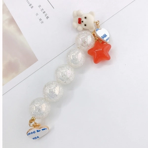 Detail of beaded mobile strap with white teddy bear, red star charm, and adhesive heart mounts