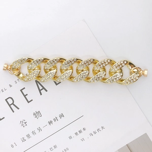Nahaufnahme des goldenen Panzerarmbands mit glitzernden Kristallen und Magnetverschluss