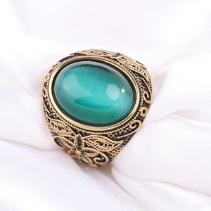 Gros plan sur une bague vintage en acier inoxydable avec pierre oeil-de-chat verte et gravures