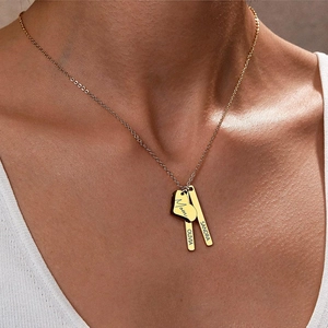 Détail d'un collier doré personnalisé avec cœur et barres porté par un mannequin