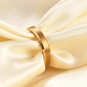 Close-up of 18K gold brushed stainless steel ring on elegant cream satin fabric