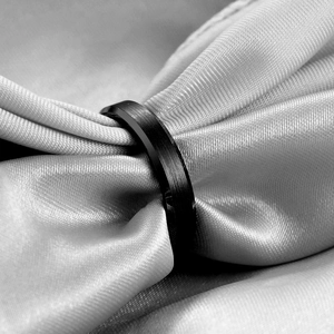 Detailed close-up of a 6mm black brushed stainless steel ring on gray silk fabric