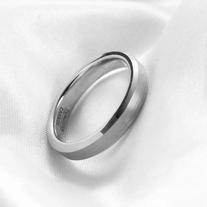 Macro shot of brushed tungsten carbide ring with polished beveled edges on white silk