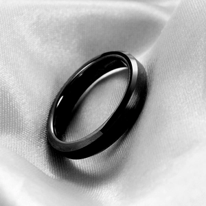 Macro shot of black brushed stainless steel ring with polished inner band on silk fabric