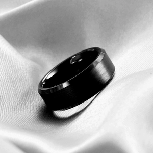 Close-up of black matte stainless steel ring with polished bevel edges on silk fabric