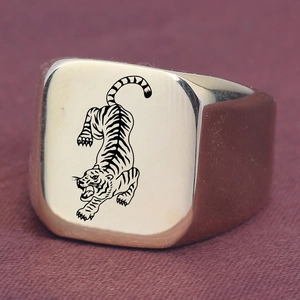 Macro shot of gold square signet ring with black tiger design on purple fabric