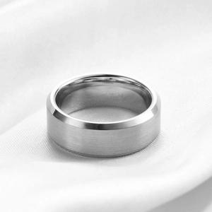 Close-up of matte silver tungsten ring with polished beveled edges on white silk fabric