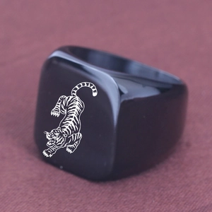 Macro shot of punk style square black signet ring featuring a laser engraved white tiger icon