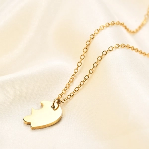 Detailed close-up of polished gold puzzle piece pendant on elegant white satin silk