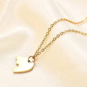 Macro shot of gold puzzle heart pendant on silk background showing fine polished texture