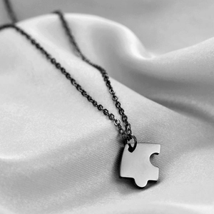 Close-up of heart puzzle piece pendant in stainless steel on silky fabric