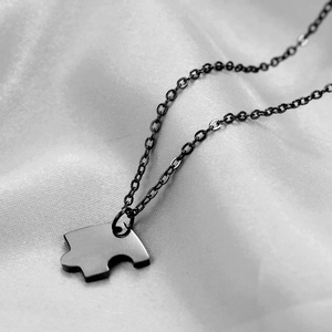 Polished stainless steel puzzle piece necklace pendant on elegant white silk background