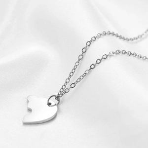 Macro shot of polished heart puzzle pendant in silver finish on white silk background